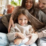 Cheerful husband keeping wife and child in arms