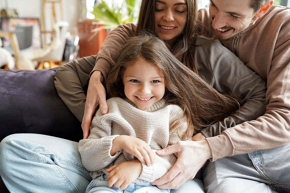 Cheerful husband keeping wife and child in arms